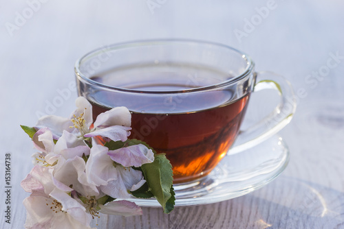 tea time/transparent cup of tea and apples flowers on white wooden table