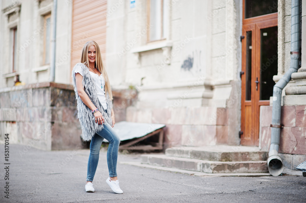 Stylish blonde woman wear at jeans and girl sleeveless with white shirt against street. Fashion urban model portrait.