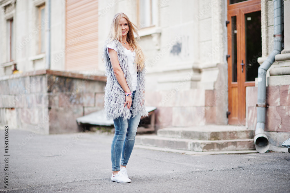 Stylish blonde woman wear at jeans and girl sleeveless with white shirt against street. Fashion urban model portrait.