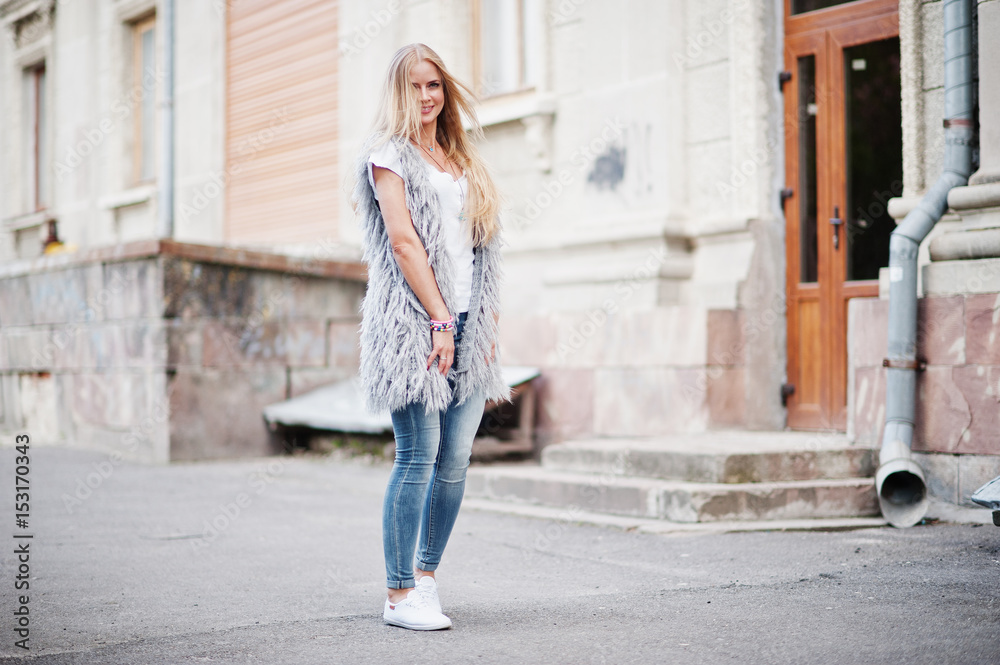 Stylish blonde woman wear at jeans and girl sleeveless with white shirt against street. Fashion urban model portrait. Stylish blonde woman wear at jeans and girl sleeveless with white shirt against street. Fashion urban model portrait.