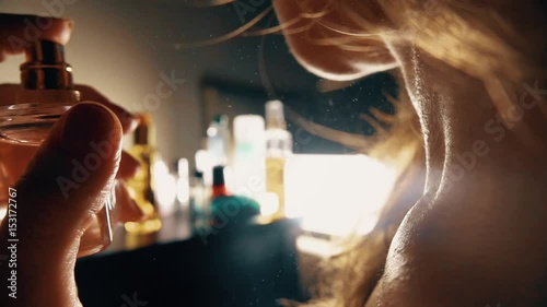 Beautiful woman spraying perfume on her neck. Slow motion close-up video photo