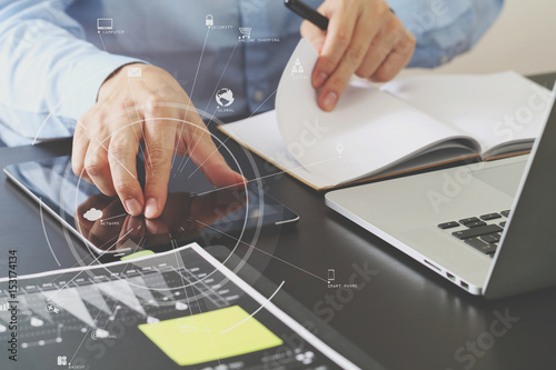 close up of businessman working with smart phone and digital tablet and laptop computer on wooden desk in modern office with virtual icon diagram