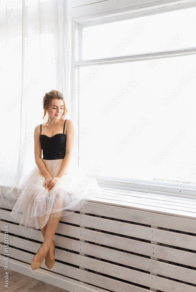 Beautiful young woman with blue eyes and white dress sitting by the window Beautiful young woman with blue eyes and white dress sitting by the window