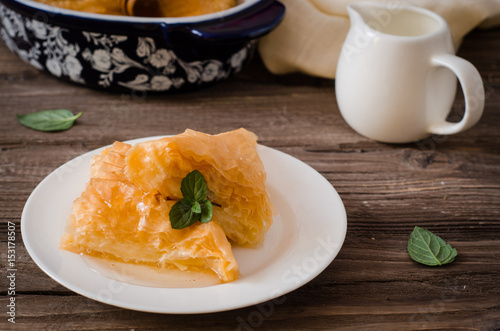 Slice of Homemade baklava stuffed cream with honey sirup on wooden table. Eastern sweets. Ramadan food