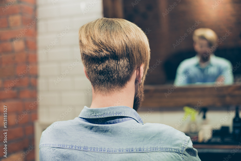 Back view of stylish trendy haircut of a bearded harsh man. He has a  fashionable hairstyle, looking at the mirror at barber shop Stock Photo |  Adobe Stock