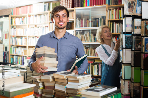 man with pile of book in book store.