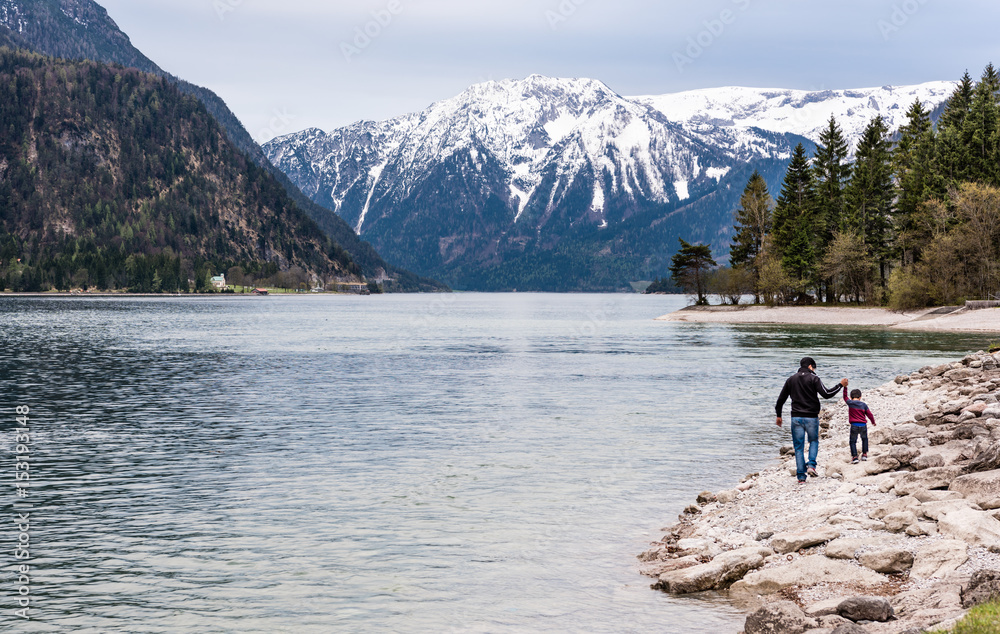 Father and his son walking and making fun on a bank of mountain lake. Family nature concept.