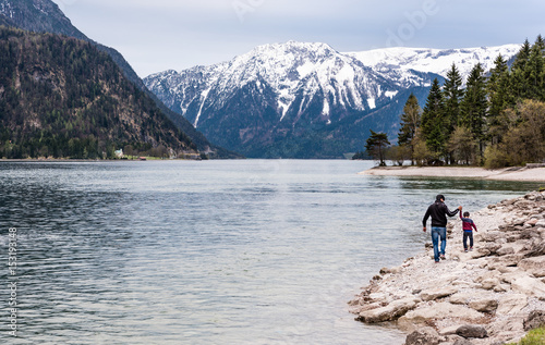Father and his son walking and making fun on a bank of mountain lake. Family nature concept.