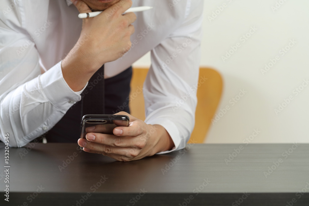 close up of businessman working with smart phone on wooden desk in modern office