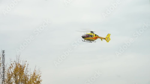 Lublin, Poland - Nowember 2016: Yellow helicopter taking off against a grey sky. Long shot. photo