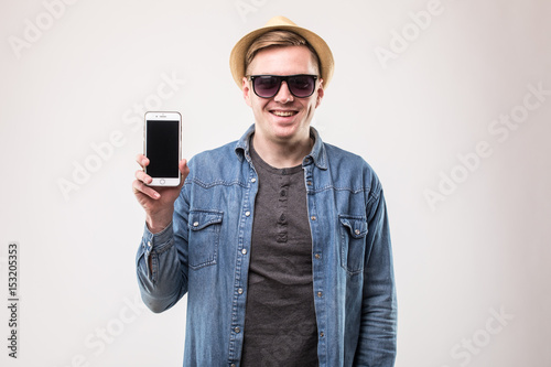 Smiling attractive young tourist show mobile phone over white background © dianagrytsku