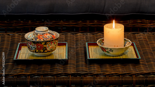 Candle and Japanese Arita porcelain ceramics on lacquer trays photo
