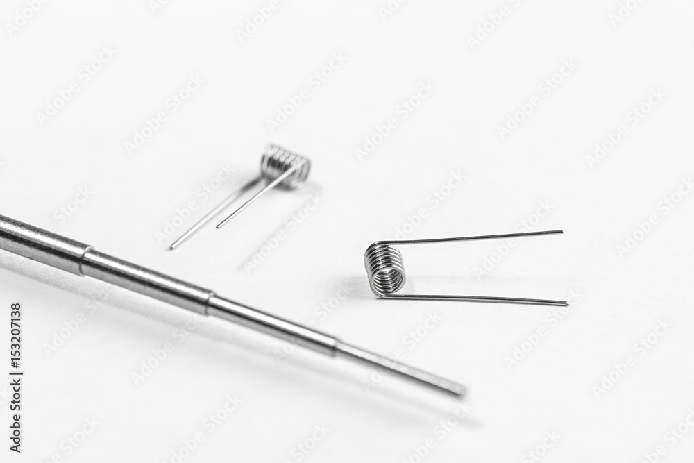 A simple Clapton coil two pieces and Micro Coil Jig on a white background isolated A simple Clapton coil two pieces and Micro Coil Jig on a white background isolated