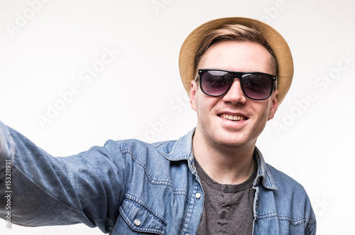 Happy man in glasses making selfie on smartphone on white background