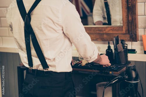 Εκτύπωση καμβά Back view of a barber shop stylist organizing his tools and equipment,  he is we