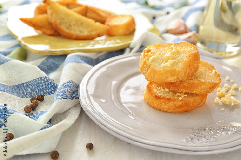 Plate with tasty garlic French bread slices on wooden table