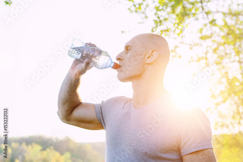 young athlete is refreshing himself with water, sport and healthy lifestyle photo