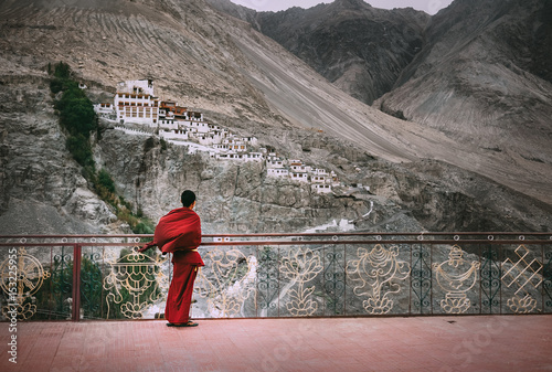Buddhist Monk in red robe looks on Diskit Monastery, Indian Himalaya, Nubra Valley photo