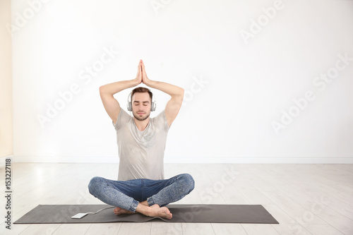 Man doing yoga and listenin...