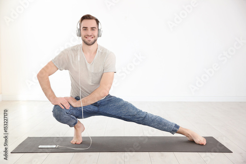 Man doing yoga and listenin...