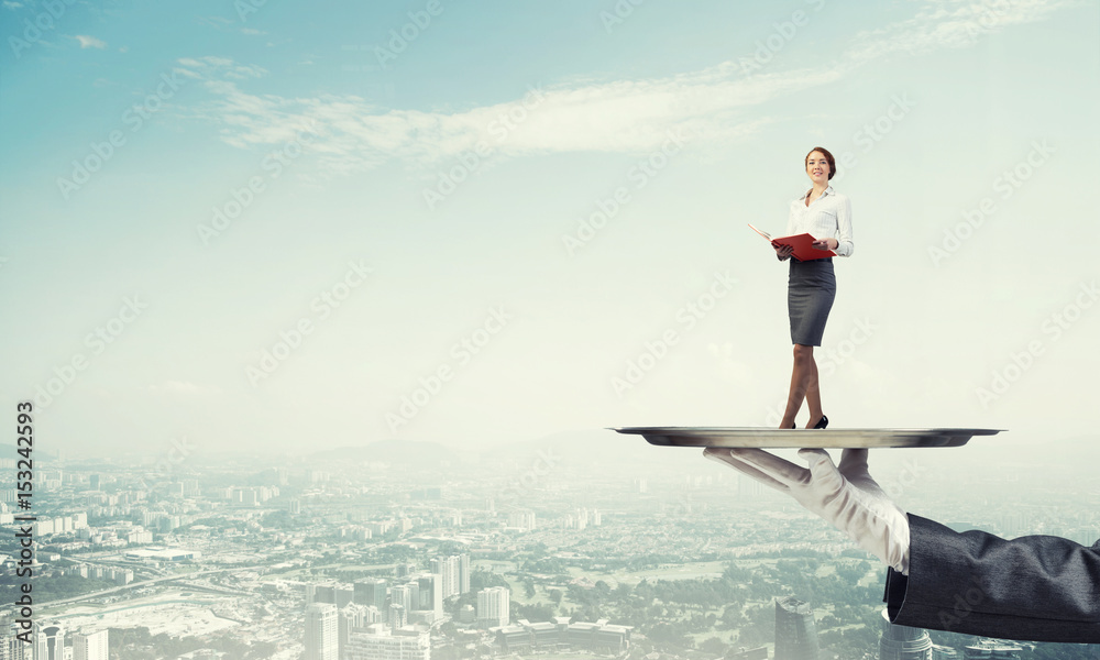 Attractive businesswoman on metal tray with red book in hands against cityscape background Attractive businesswoman on metal tray with red book in hands against cityscape background