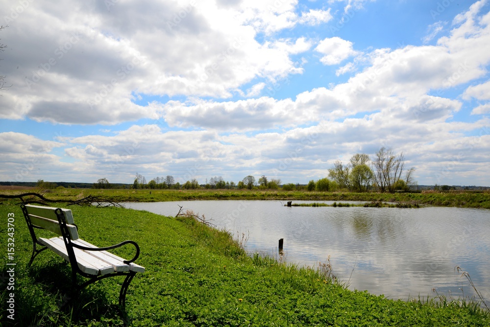 White bench on the shore of the lake and blue sky