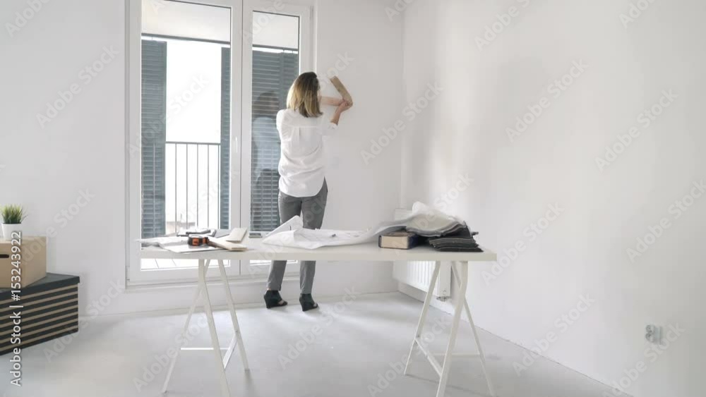 Young woman with blueprints checking colour for wall at her new home
Young woman with blueprints checking colour for wall at her new home