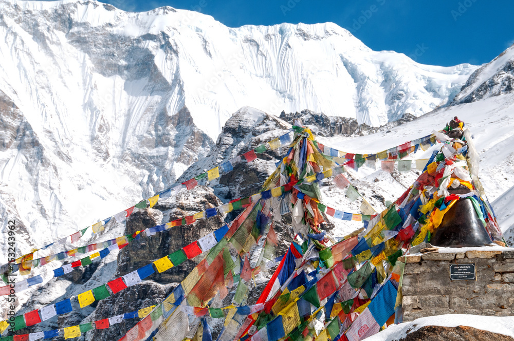 Buddyjskie flagi modlitewne w Annapurna Base Camp z ośnieżonymi górami w tle.. 