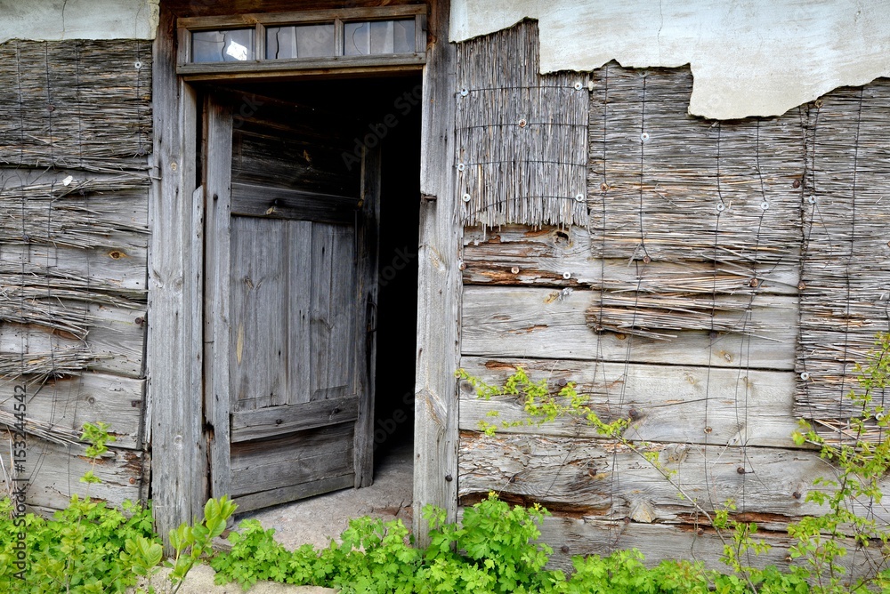 Open door of old wooden abandoned house destroying in the wilderness
