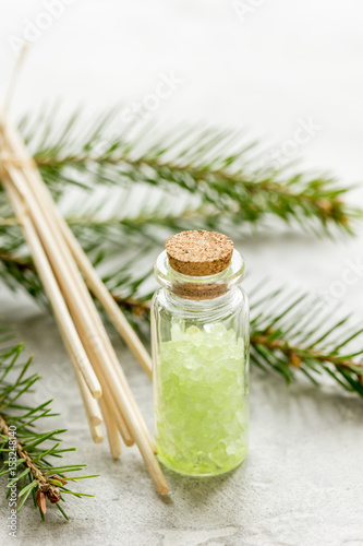 cosmetic spruce salt in bottles with fur branches on white table background
