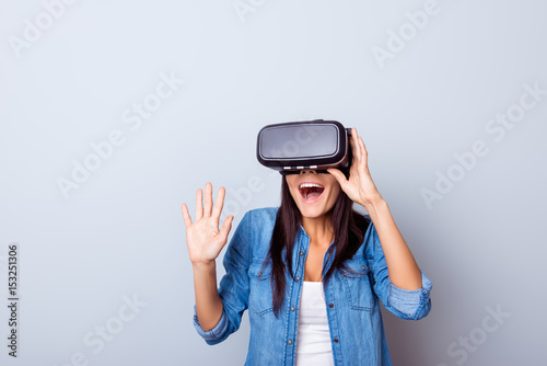 Wow! Excited latinn girl in a VR glasses surprised with what she saw. She is touchinmg sonmething and express the emotions from this experience