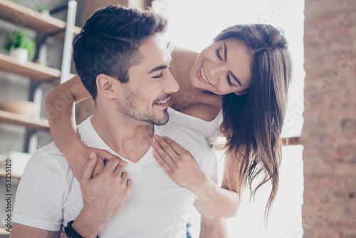 Fotografija Beautiful couple of young lovers are hugging indoors at home, looking at each ot