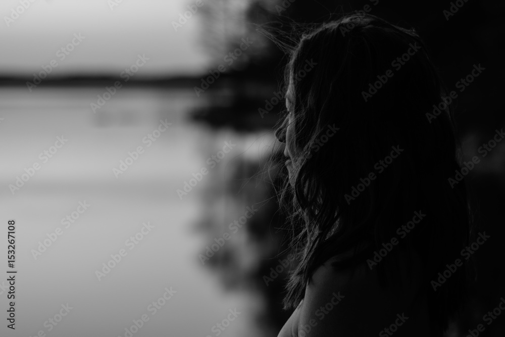Young woman on the beach looking at water black and white