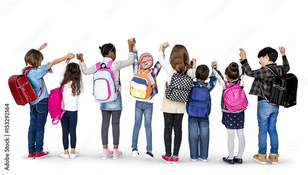 Obraz premium Rear view group of diverse kids standing in a row holdings hands in the air