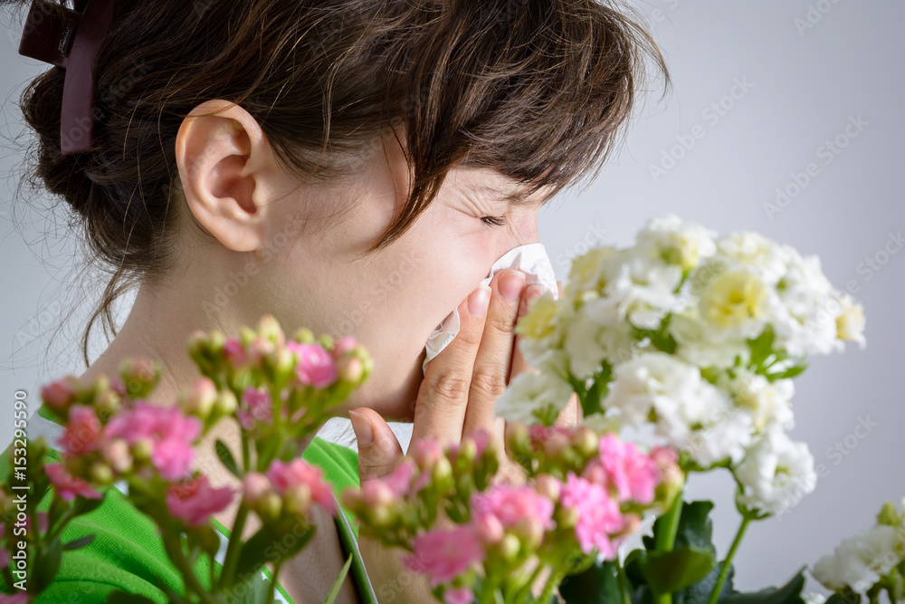 Woman with handkerchief and pollen allergy near flowers Woman with handkerchief and pollen allergy near flowers