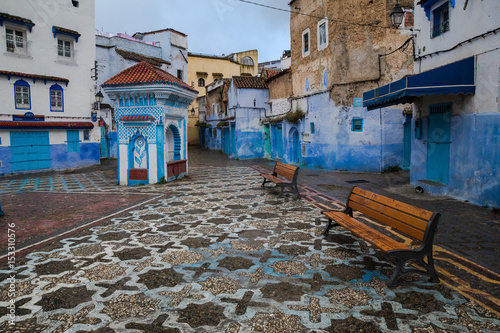 Mosaic square with benches and a small pavilion in a blue city © Евгений Усатов