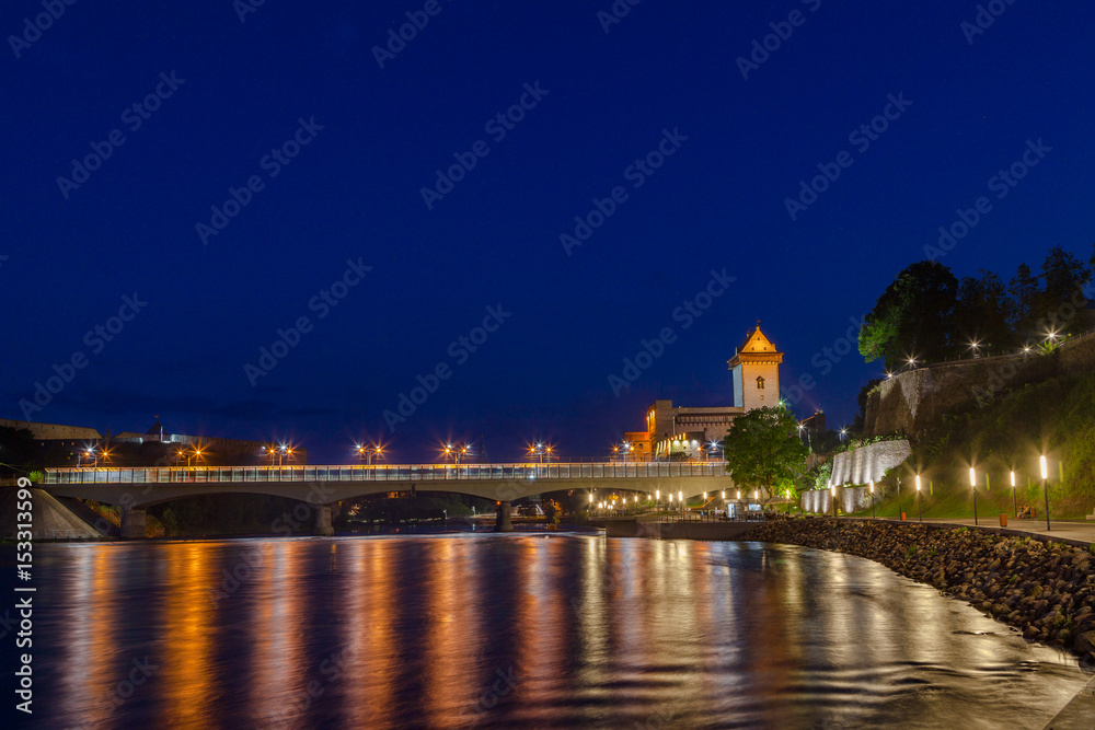 Illuminated medieval fortress and moderm bridge on the river Narva, Estonia and Russia border. Blue hour