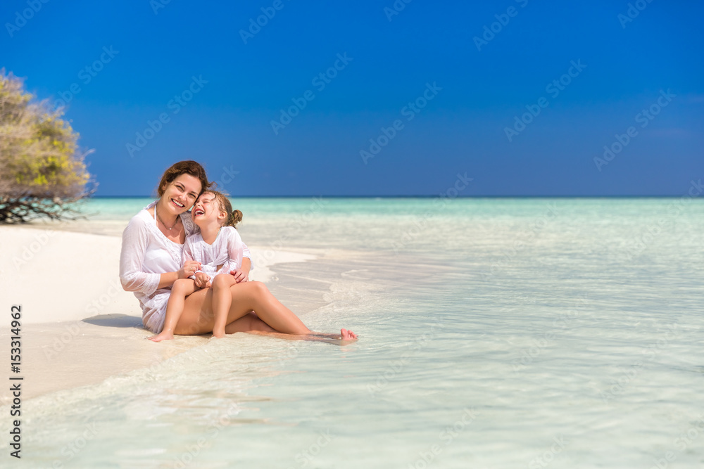 Mother and little daughter playing on sunny beach