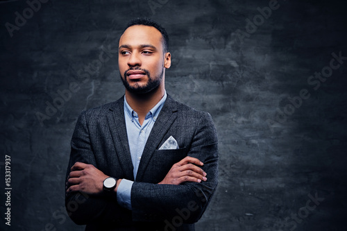 A luxury black male dressed in a suit over grey vignette background. © Fxquadro
