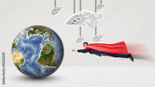A small businessman in a superhero cape flying towards a tiny earth globe with white paper comets hanging above him.
