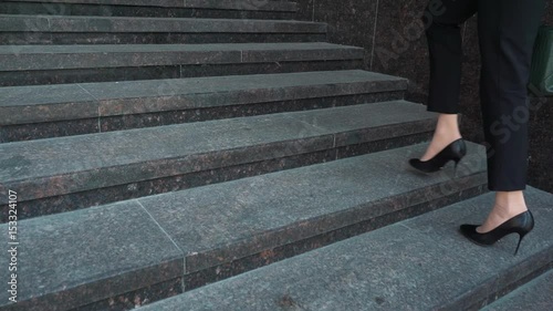 Lower part of business woman in formal suit walking up the outdoor stair. photo