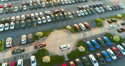 Dealership car lot, many beautiful new vehicles for sale, many brands, aerial view.
