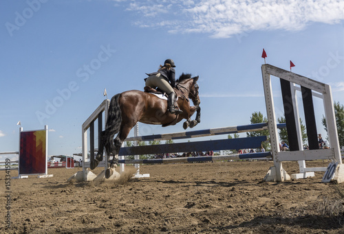 Low angle view of an Equestrian Rider clearing jump, view from the ground and behind the horse and rider
