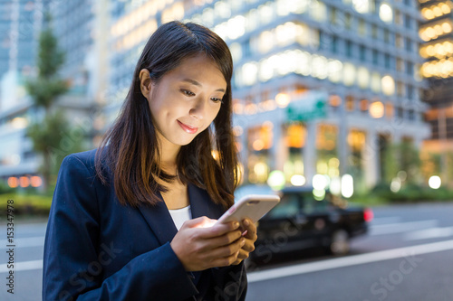 Canvas Print Businesswoman sending sms on mobile phone in Tokyo city at night