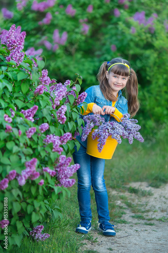Cute adorable beautifull lady woman girl with brunette hair on a meadow of lilac purple bush.People in jeans wear.