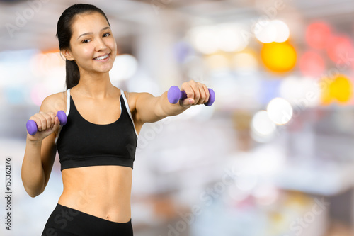 Happy fitness woman lifting dumbbells