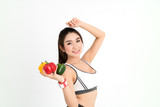 Happy young asian fitness woman stand and holding the red,yellow,green of bell pepper,and wear smart watch for tracking heart rate monitor on white background