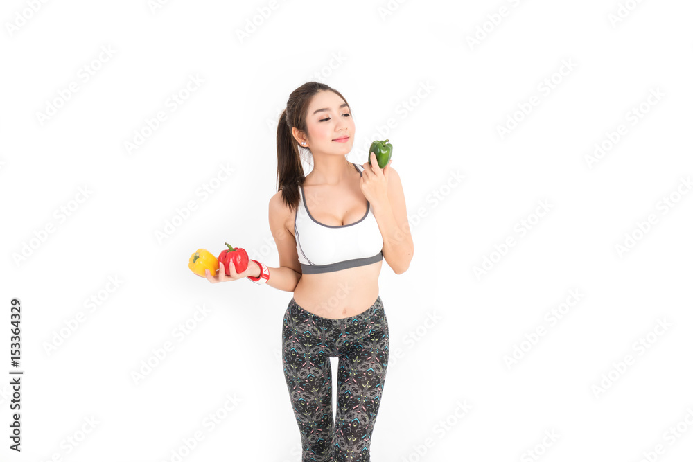 Happy young fitness woman stand and holding the red,yellow,green of bell pepper,and wear smart watch for tracking heart rate monitor on white background Happy young fitness woman stand and holding the red,yellow,green of bell pepper,and wear smart watch for tracking heart rate monitor on white background