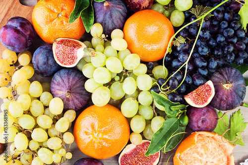 Fototapeta Naklejka Na Ścianę i Meble -  Healthy Food Background with Colorful Fruit. Grape, Orange, Figs and Plum with Green Leaves