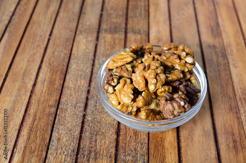 Walnuts in bowl over wooden background